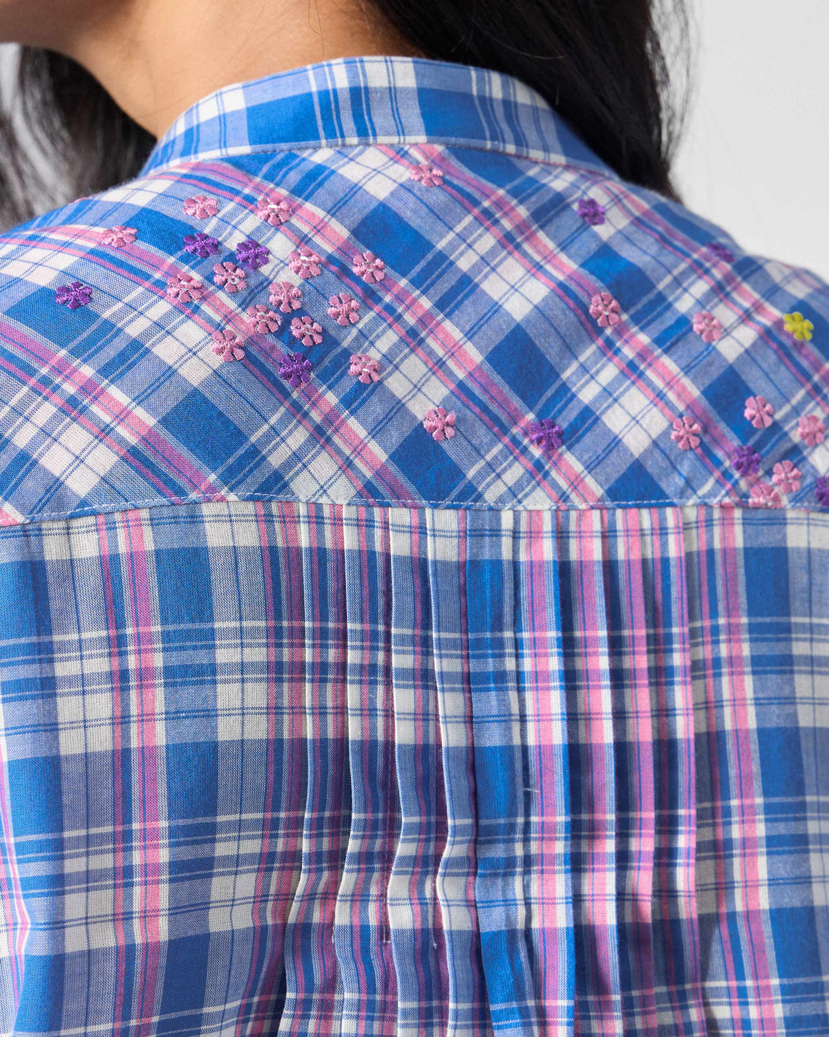 Close-up of pink floral embroidery on the bias yoke of a blue Eka Kurta.