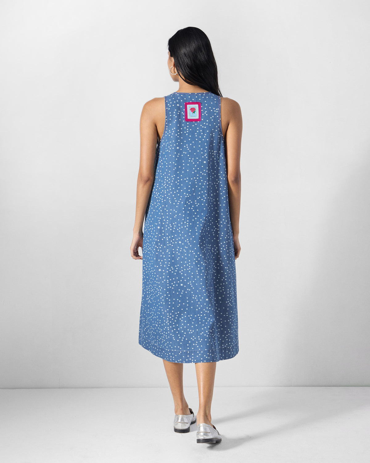 Back of a blue star-print midi dress with a pink rose patch.