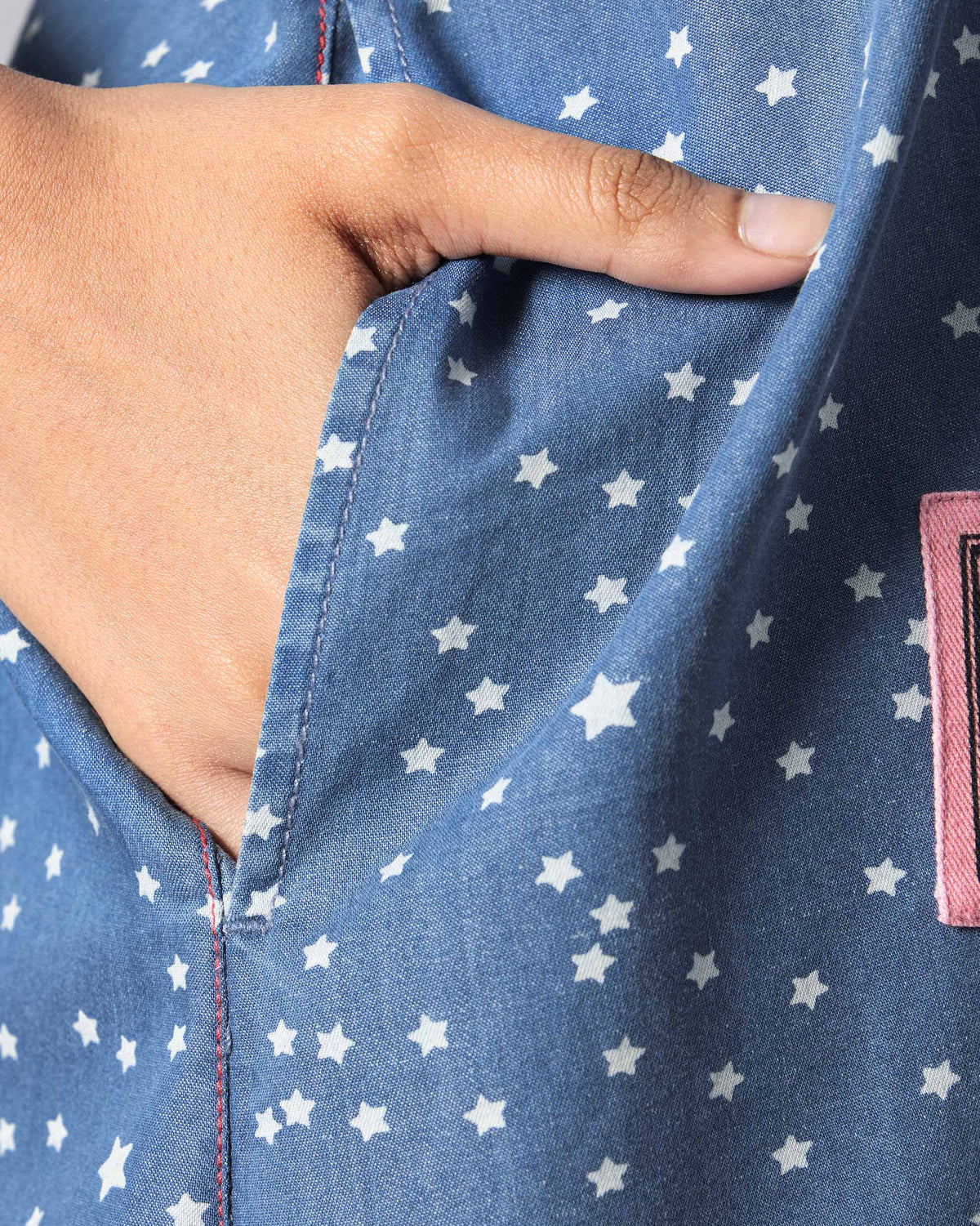 Close-up of a blue star-print dress pocket with a hand inside.