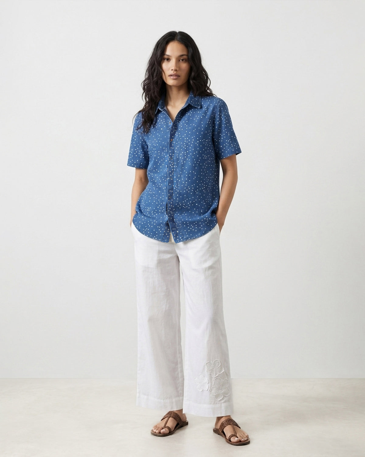 Person wearing a denim Spark shirt with a white star print over white trousers.