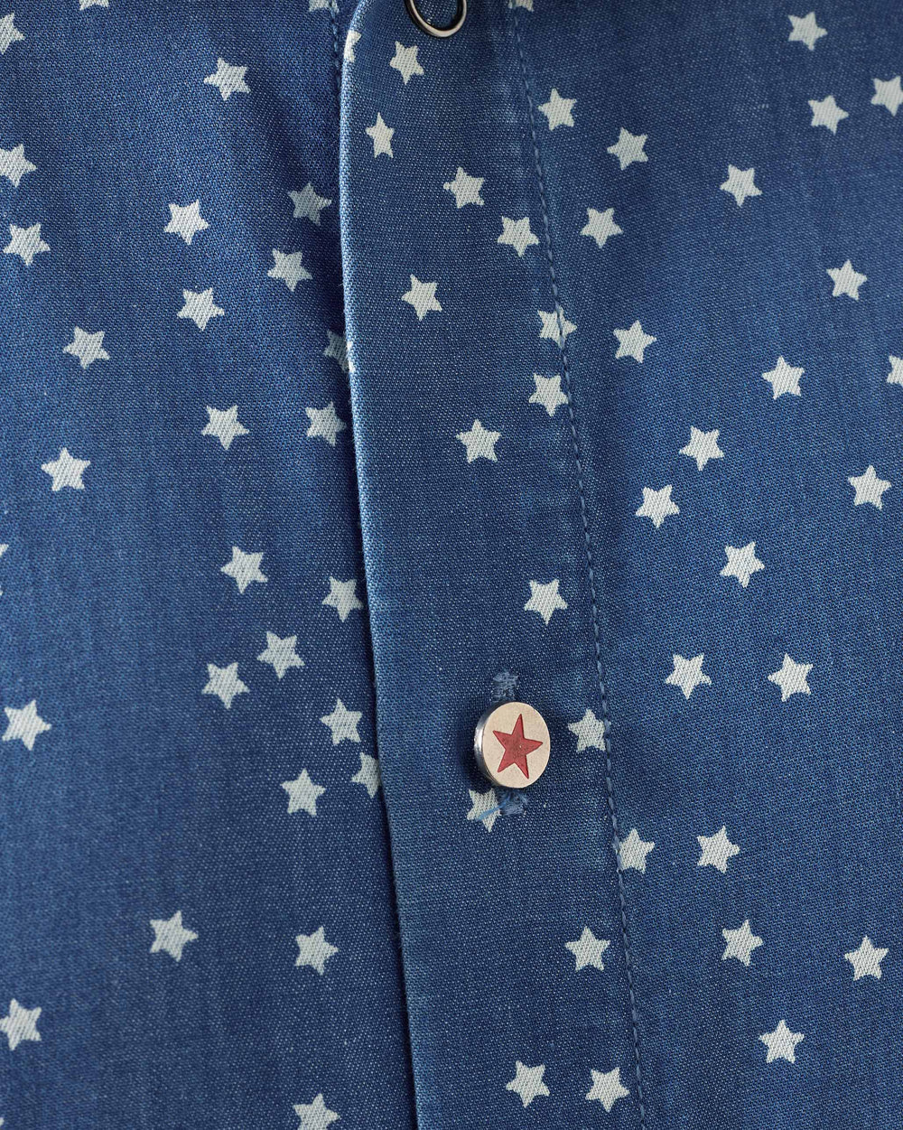 Close-up of a denim Spark shirt placket with a silver button and red star.