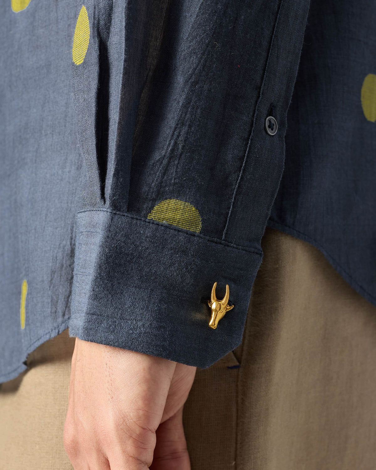Close-up of a charcoal Nawab Shirt cuff with chartreuse dots and a gold Nandi detail.