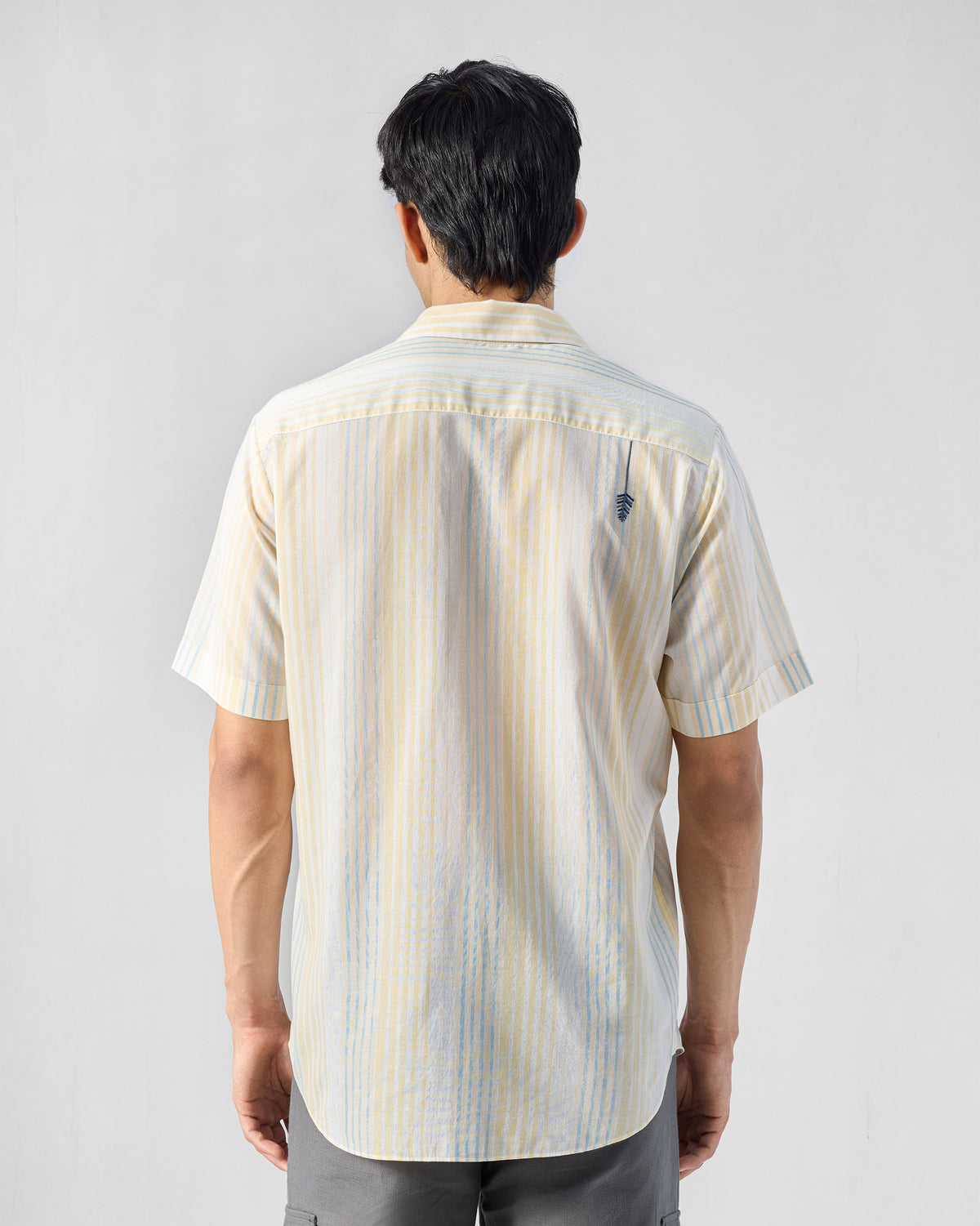 Back of a yellow and blue striped Flow Half Sleeve Shirt with a small embroidered leaf.