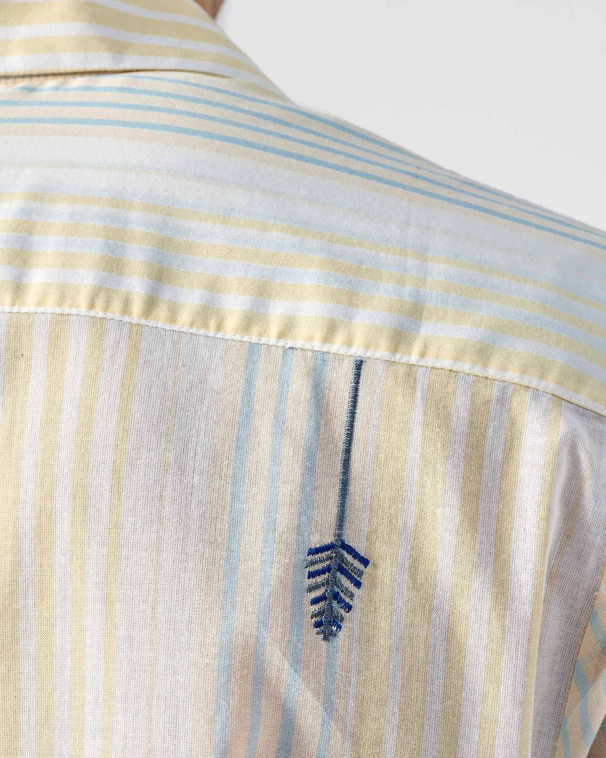 Close-up of the back yoke on a striped Flow Half Sleeve Shirt with a feather embroidery.