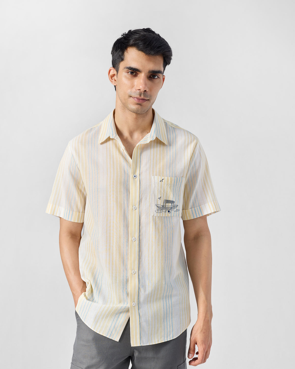 Person wearing a yellow and blue striped Flow Half Sleeve Shirt with a boat-embroidered pocket.