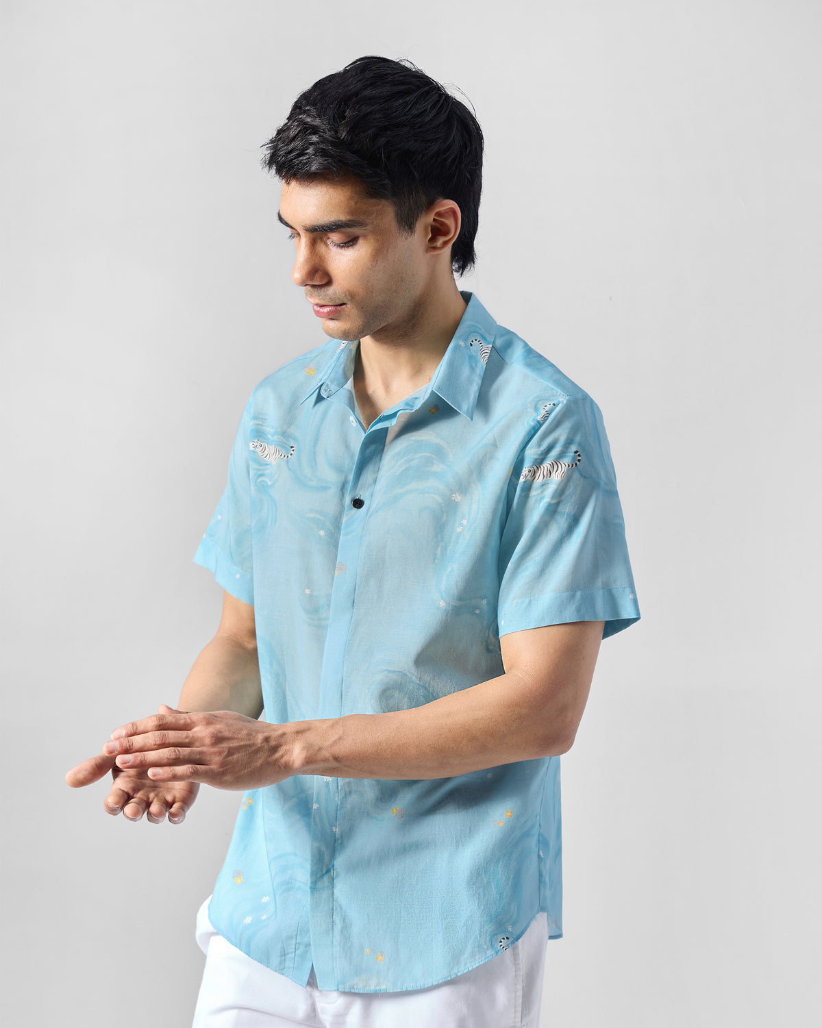 Person wearing a light blue printed Riverine shirt with tiger embroidery.