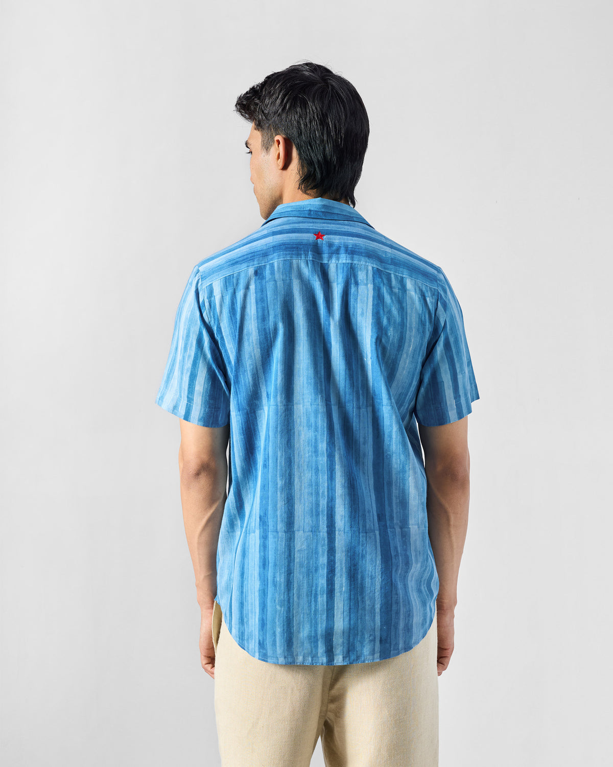 Back of a blue Ganga shirt with a small red star.