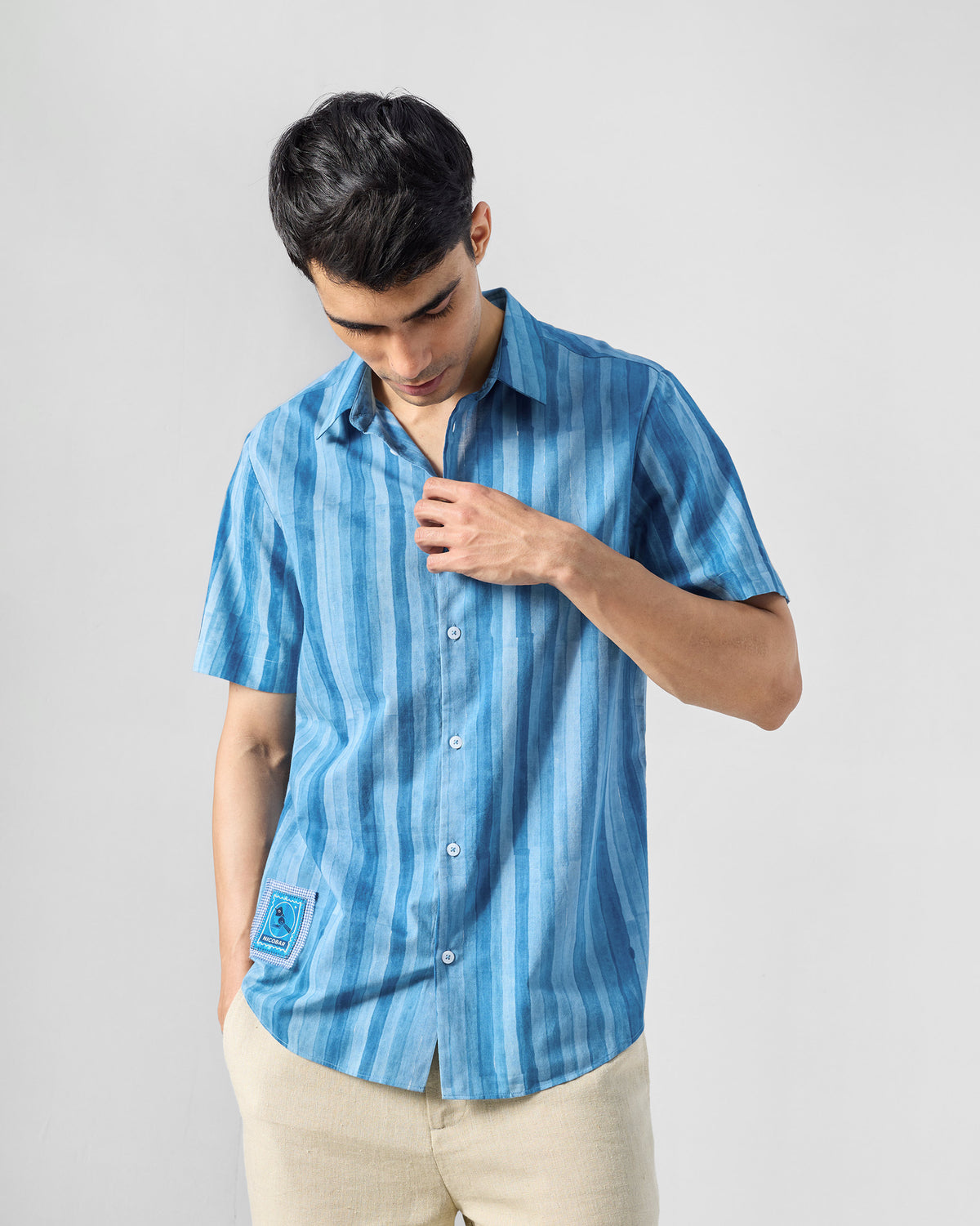 Person wearing a blue Ganga shirt with a patch near the hem.