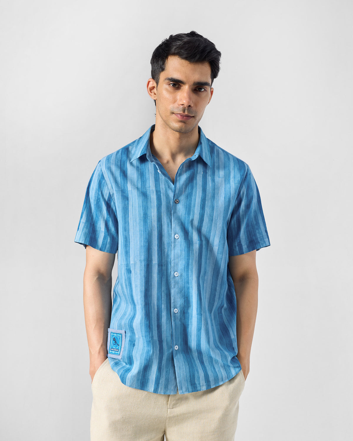 Person wearing a blue Ganga shirt with a bird patch at the hem.