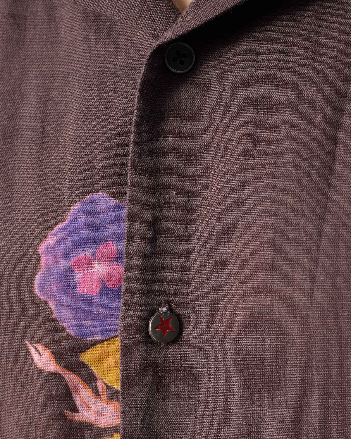 Close-up of a brown Mistari shirt placket with a red star button.