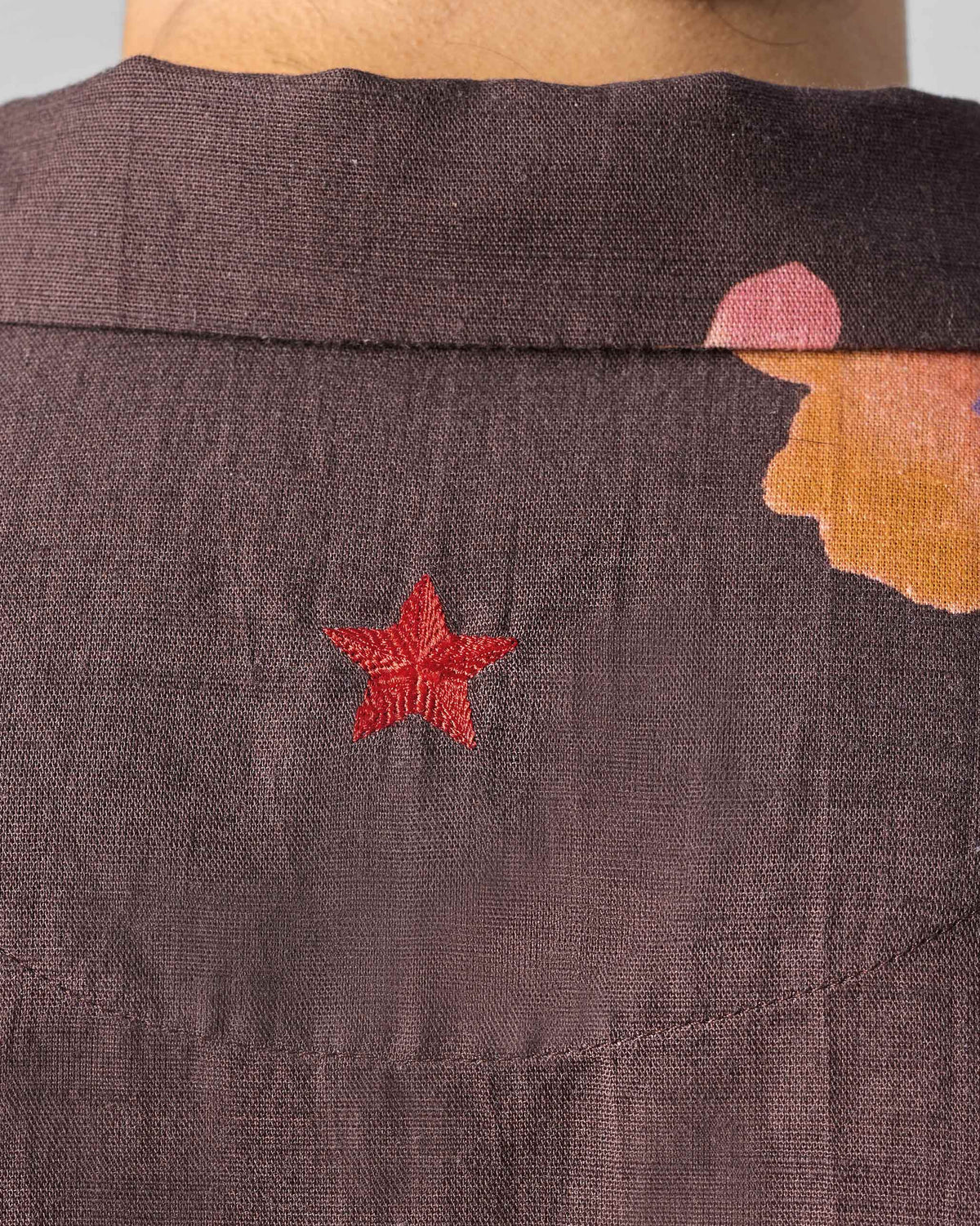 Close-up of a red star on the back of a brown Mistari shirt.