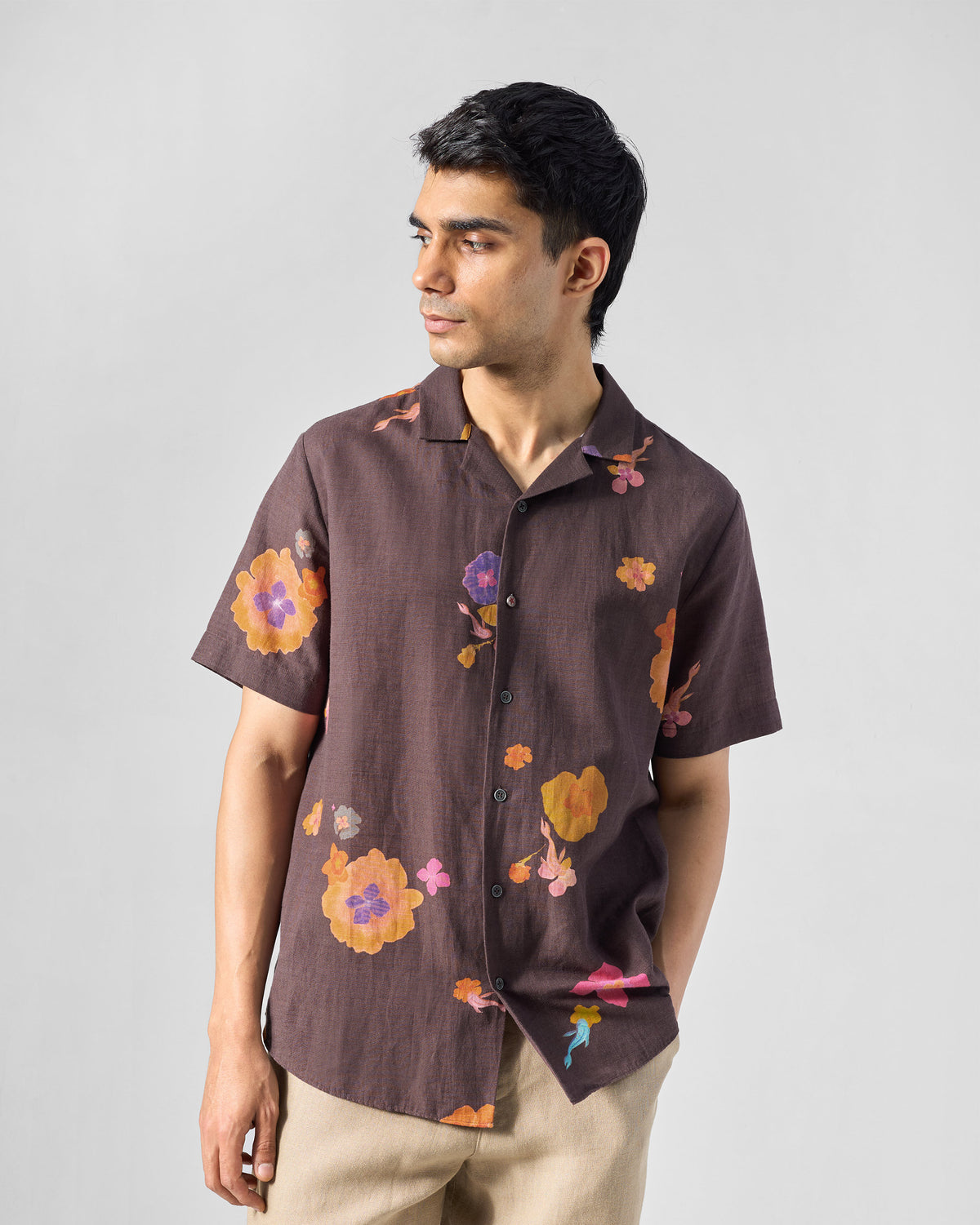Person wearing a brown Mistari shirt with orange and magenta floral print.