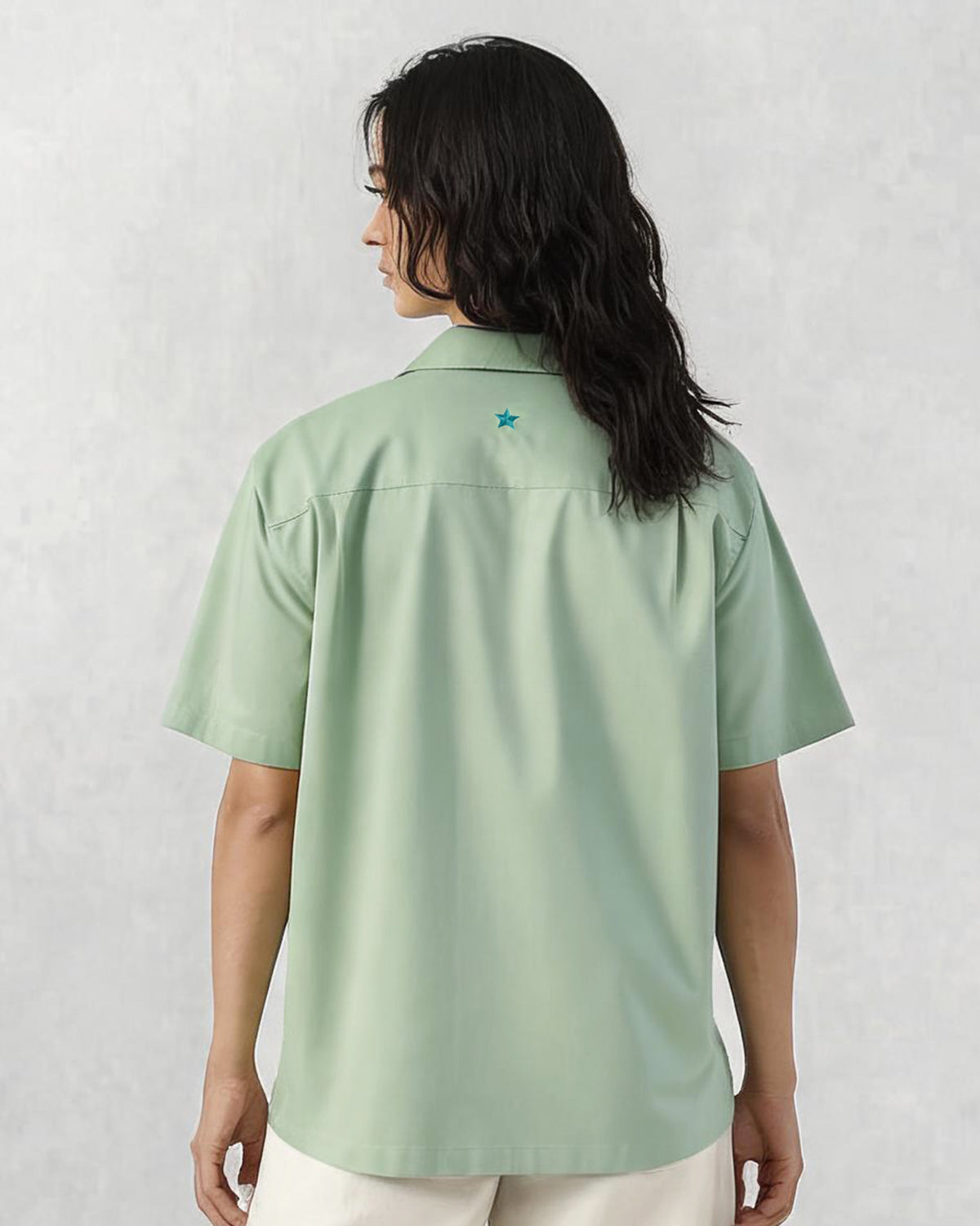 Back of a sage green Jaisal Shirt with a teal star at the yoke.