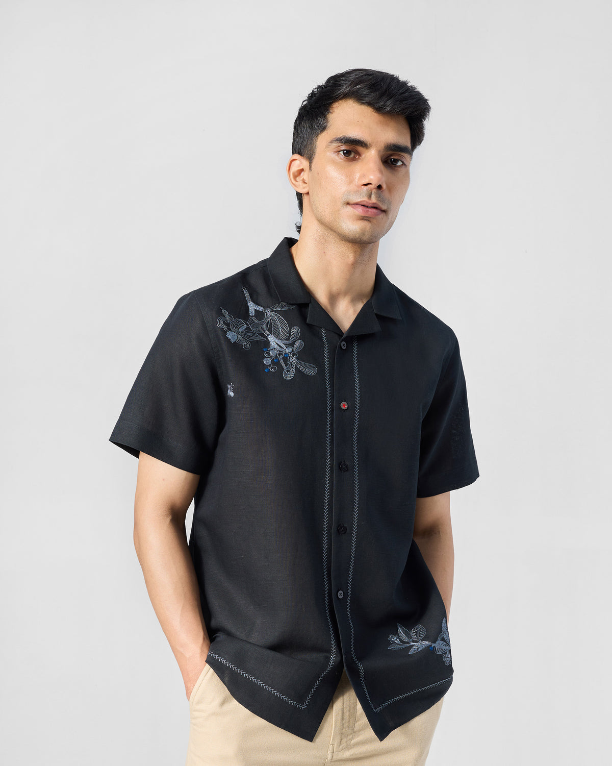 Person wearing a black Delta shirt with blue floral embroidery and contrast placket stitching.
