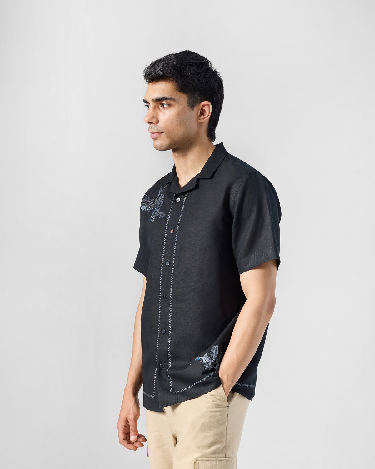 Side view of a black Delta shirt with camp collar and placement embroidery.