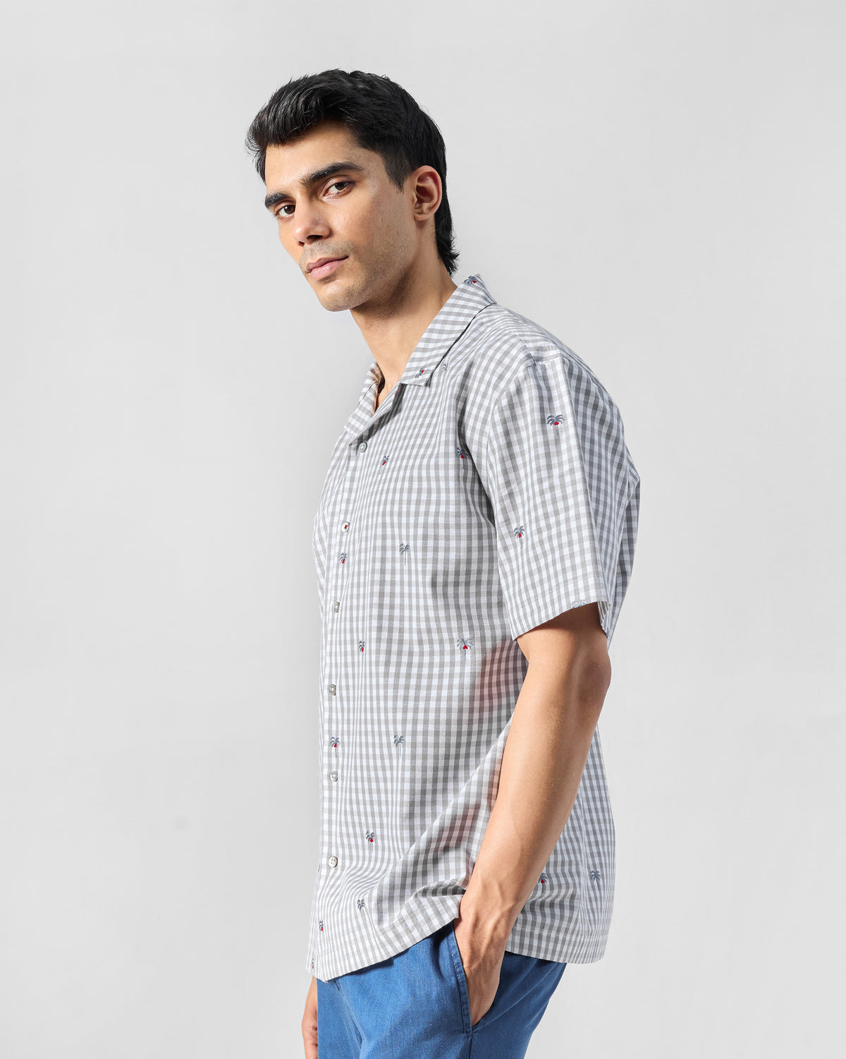 Side view of a charcoal and white gingham Bena shirt with palm tree embroidery.