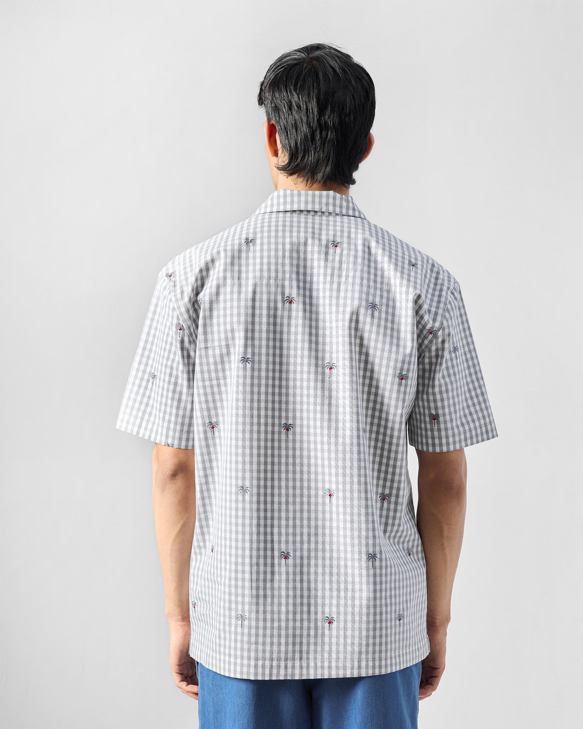 Back of a charcoal and white gingham Bena shirt with palm tree embroidery.