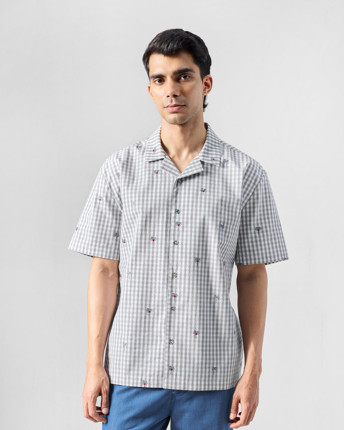 Person wearing a charcoal and white gingham Bena shirt with a camp collar.