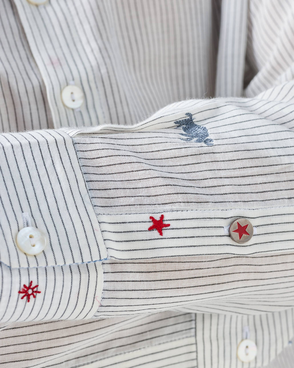 Close-up of animal embroidery on a charcoal and white Bageecha kurta sleeve.