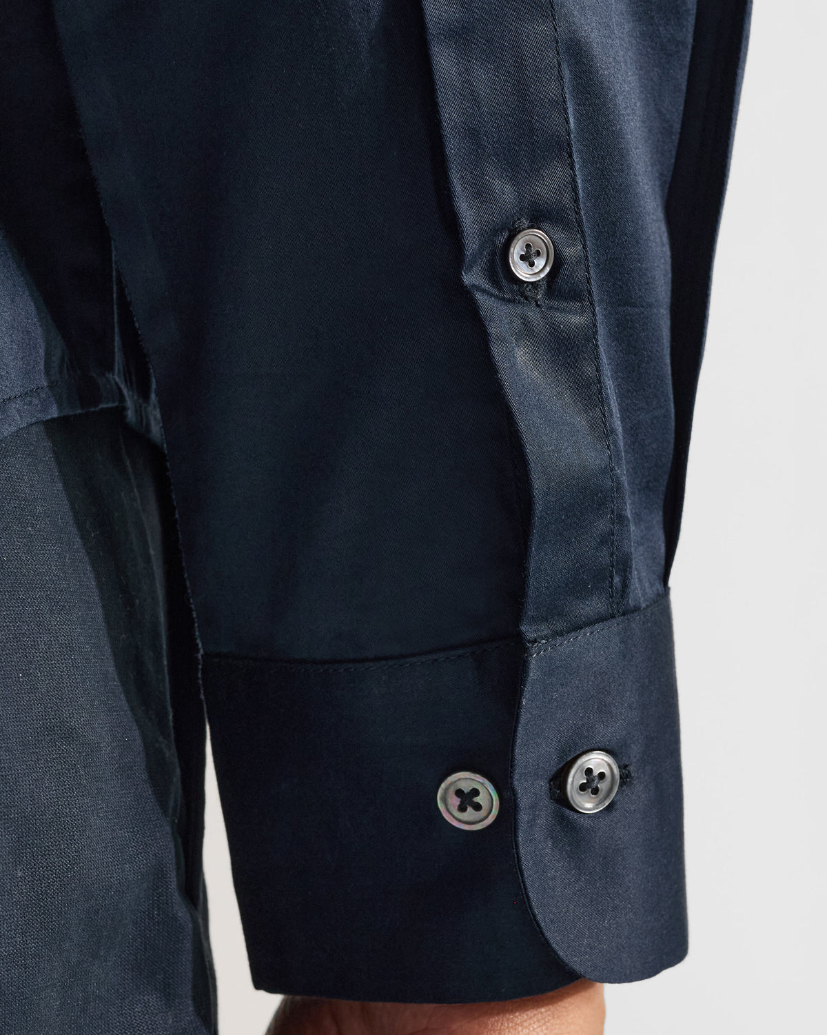 Close-up of a navy Nightjar shirt cuff with pearl buttons.