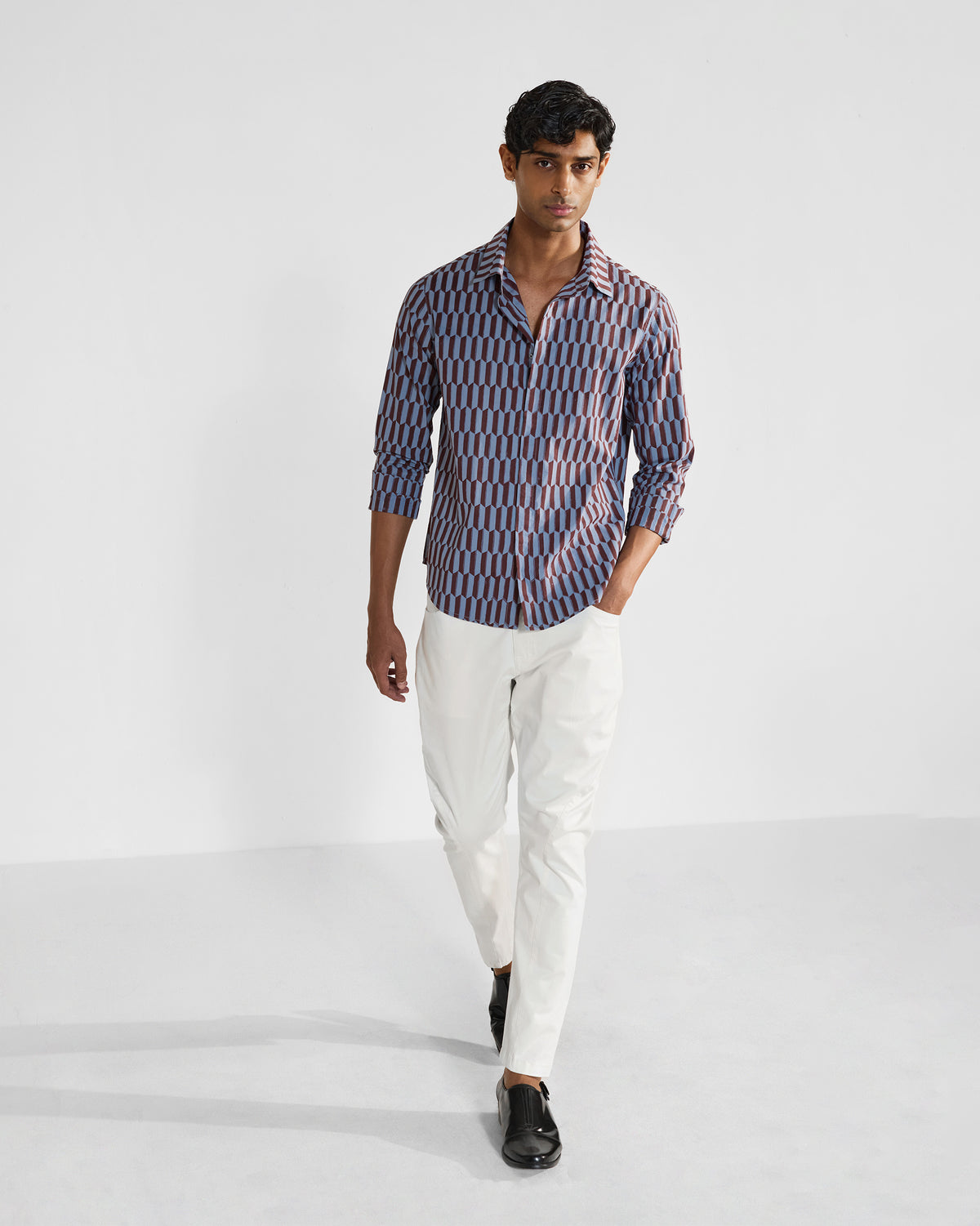 Person wearing a brown and light blue geometric print Drongo shirt untucked.