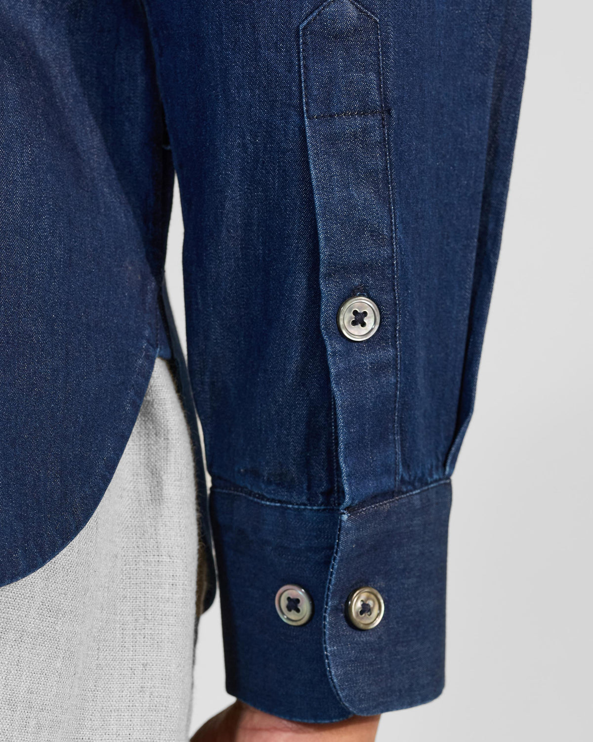 Close-up of an indigo Loris shirt cuff and curved hem.