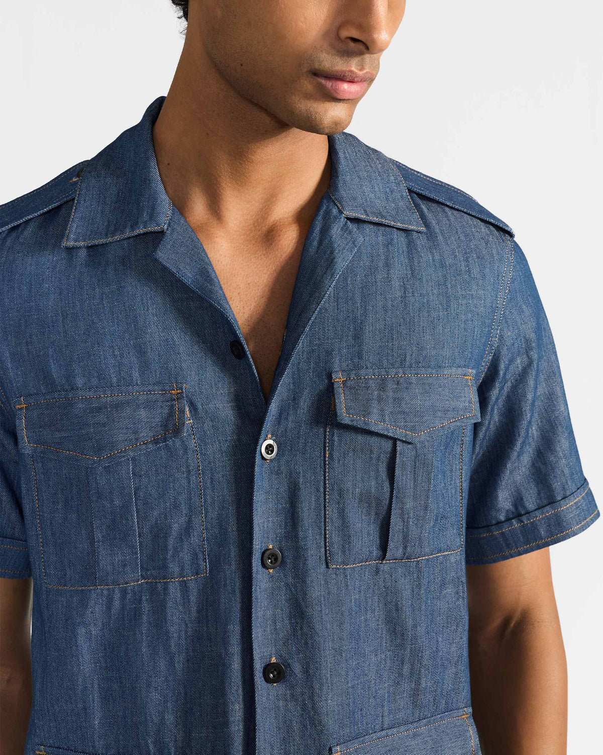 Person wearing a blue denim Sambar shacket with pleated chest pockets.