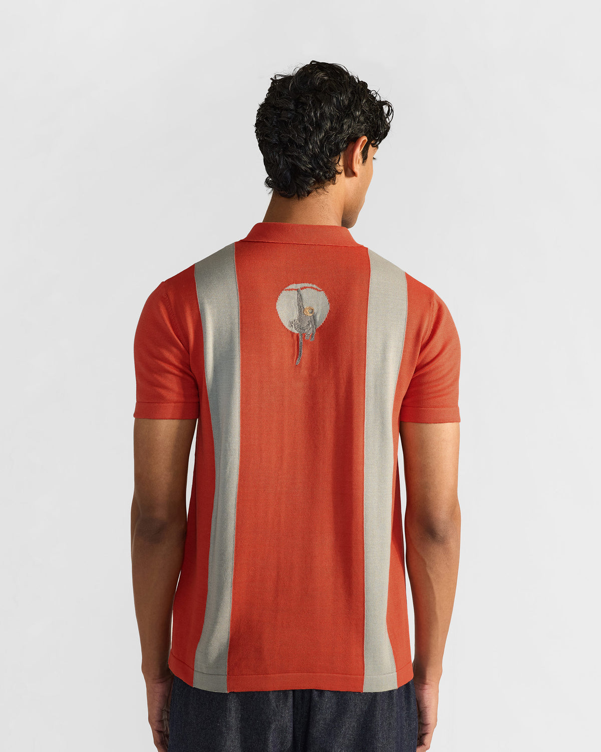 Bonnet Polo back view with grey stripes and circular monkey graphic.