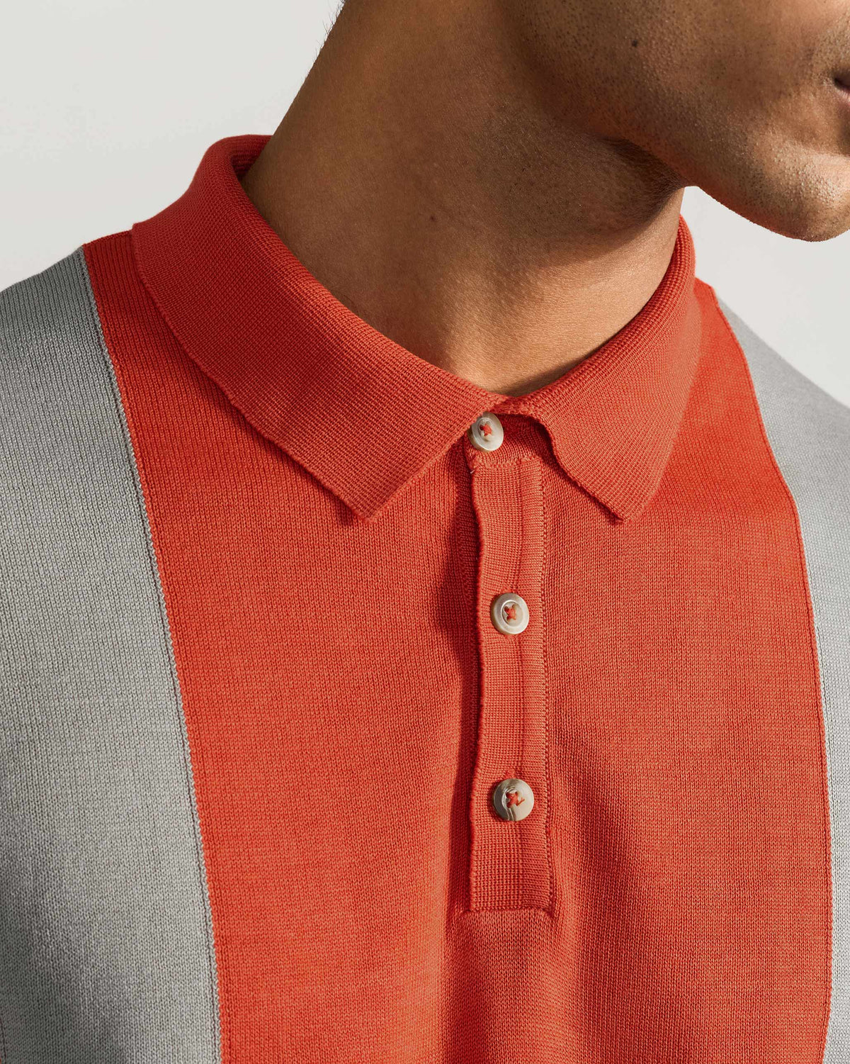 Close-up of Bonnet Polo collar and button placket on rust and grey knit.