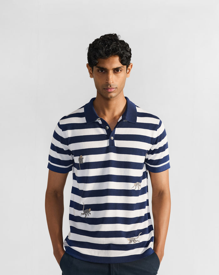 Person wearing a navy-and-white striped polo with embroidered macaques.