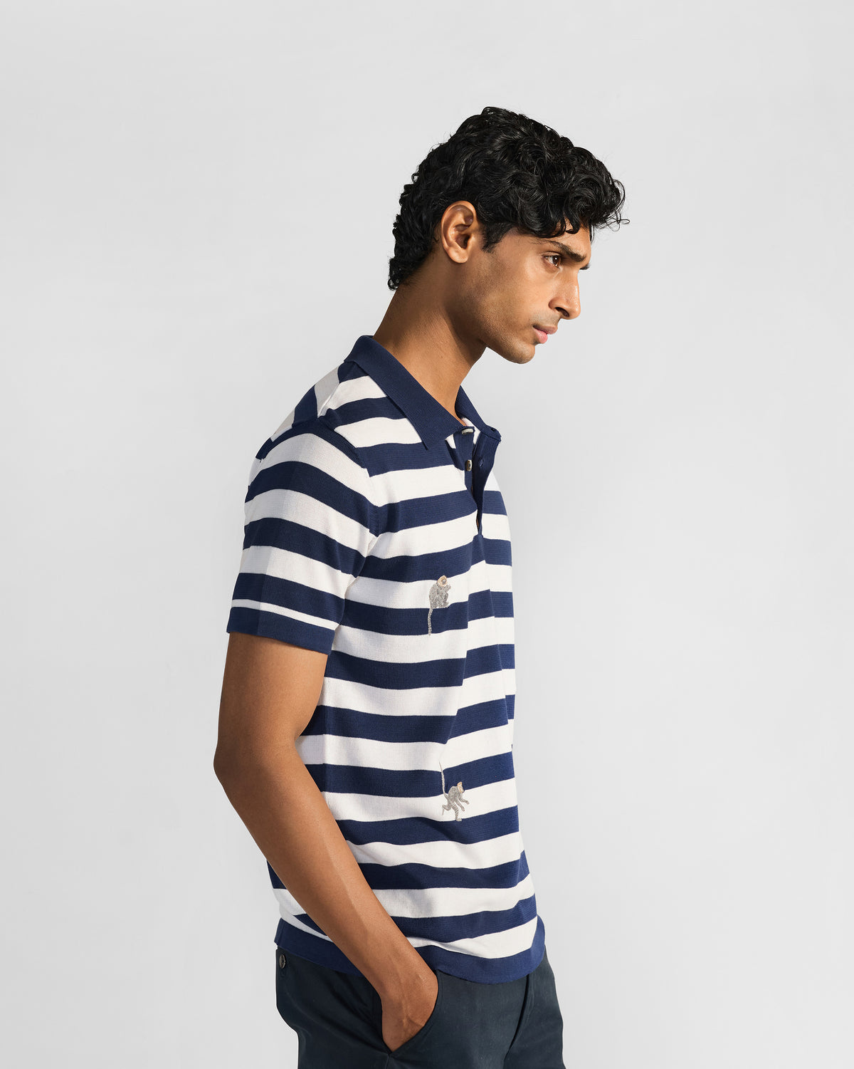 Side view of a navy-and-white striped polo with embroidered macaques.