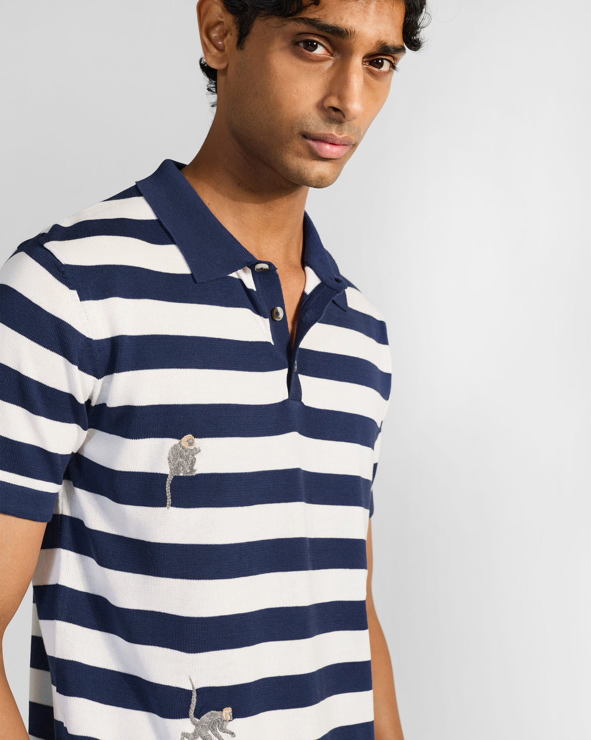 Navy-and-white striped polo with a navy placket and embroidered macaques.