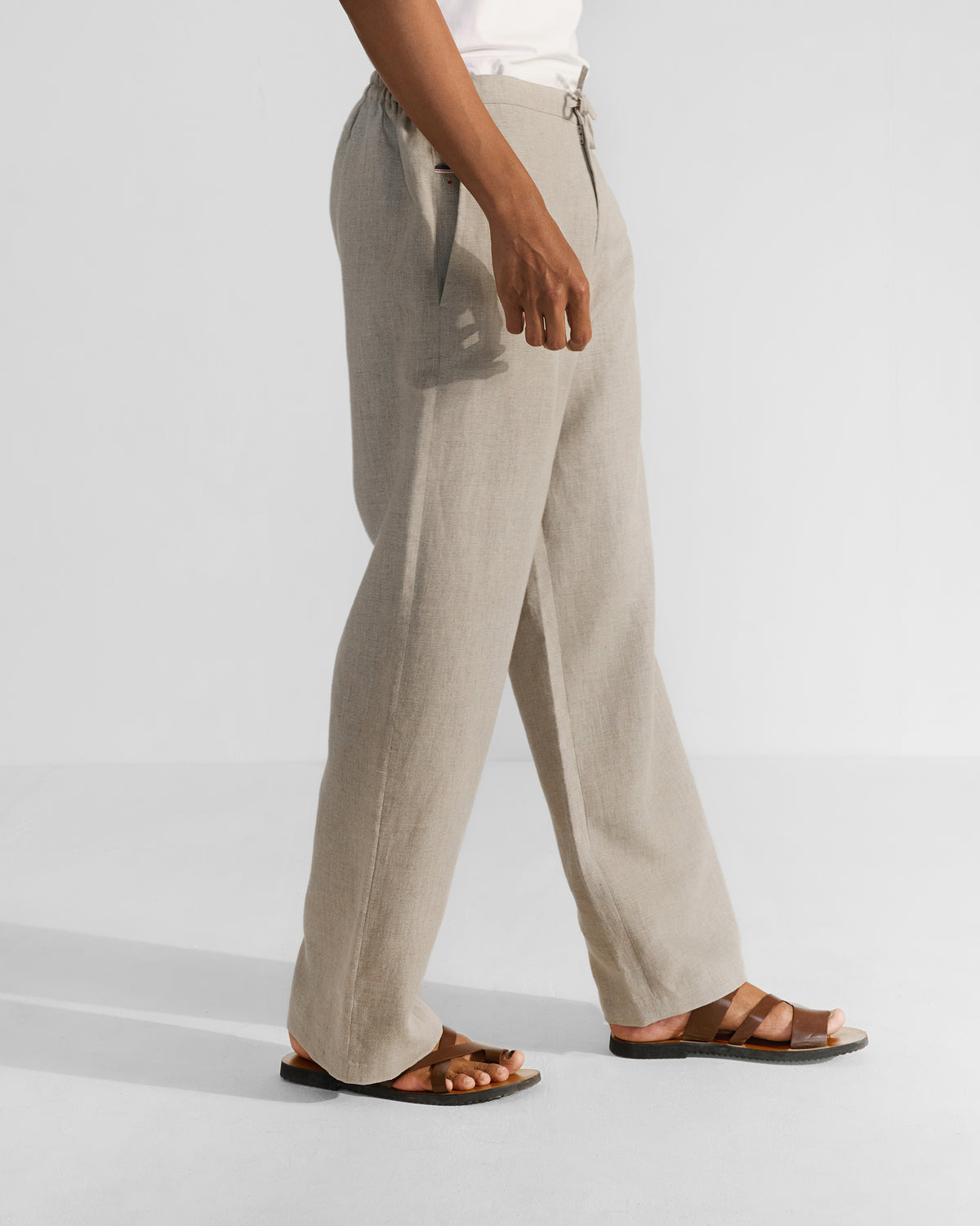 Side view of beige Ibex Trousers showing a side pocket and straight-leg silhouette.
