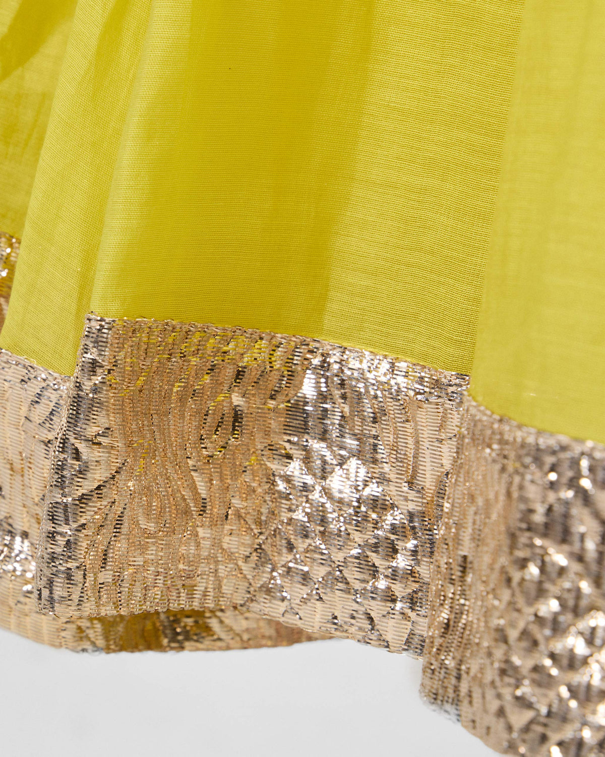 Close-up of the gold metallic border along a yellow Cherai kurta hem.