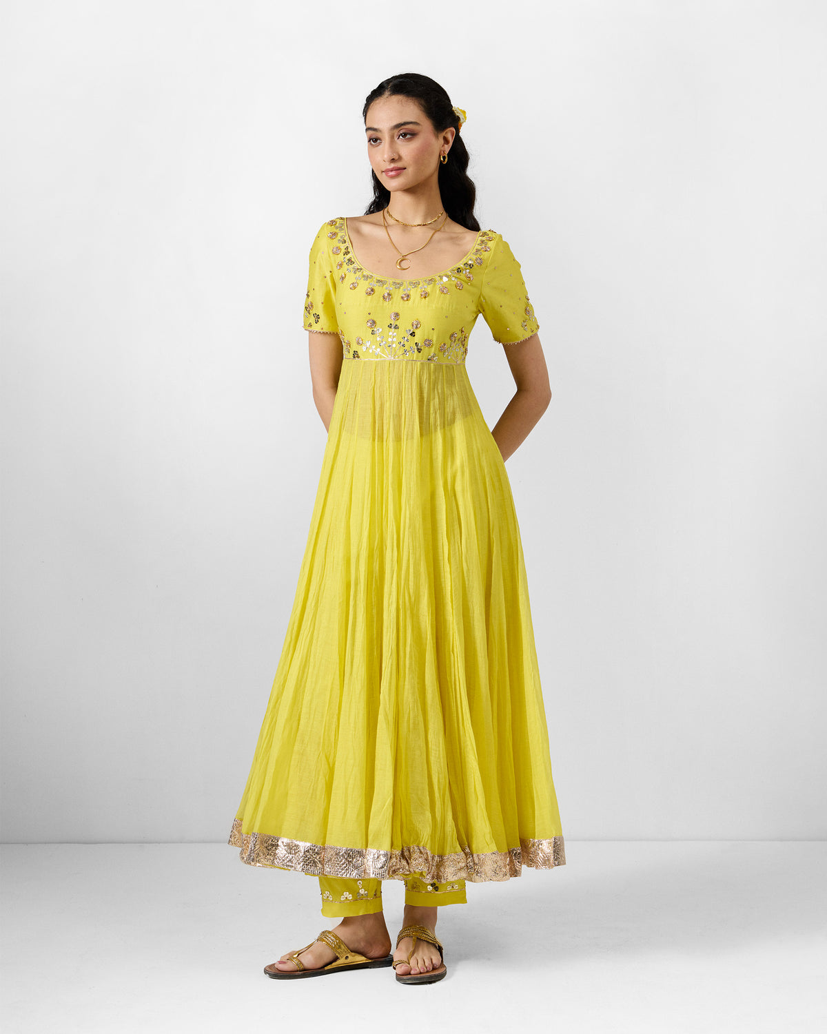 Person wearing a yellow Cherai kurta with gota embroidery at the neckline and a gold hem.