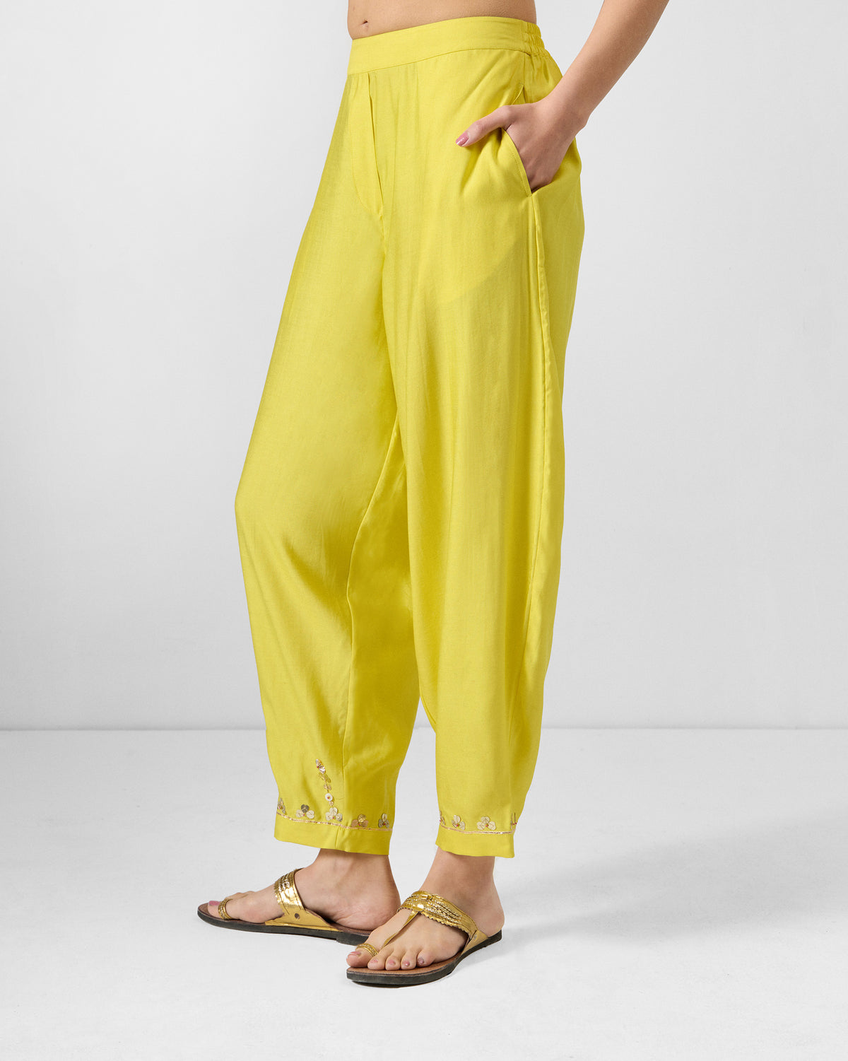 Side view of yellow Lebong pants with gold sequin hem embroidery.