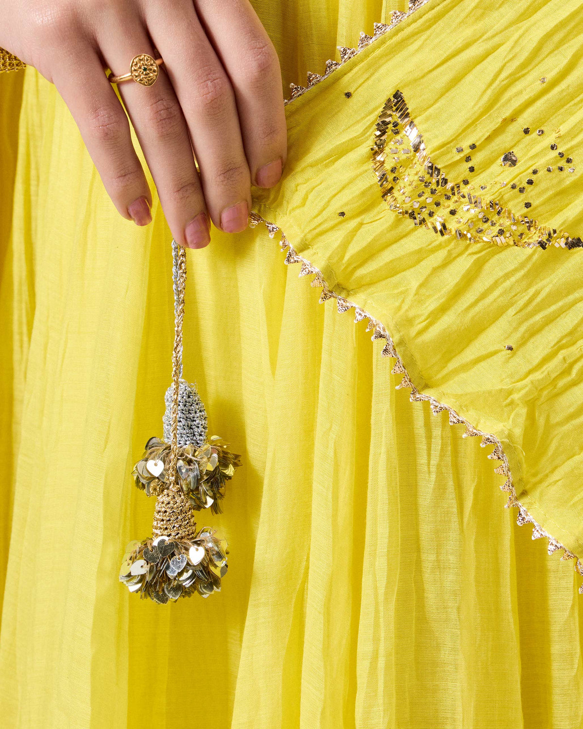 Close-up of a yellow Shanti dupatta with a sequined tassel and gold gota border.