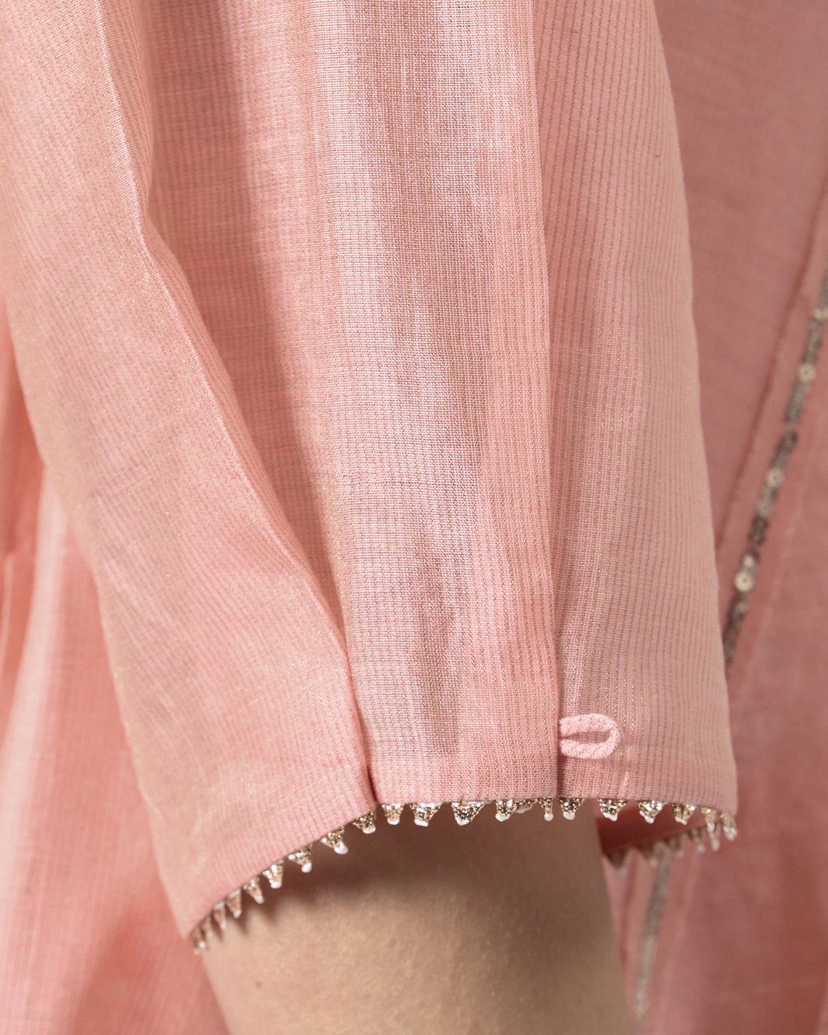 Close-up of the scalloped metallic sleeve trim on a pink embroidered Sukhna kurta.