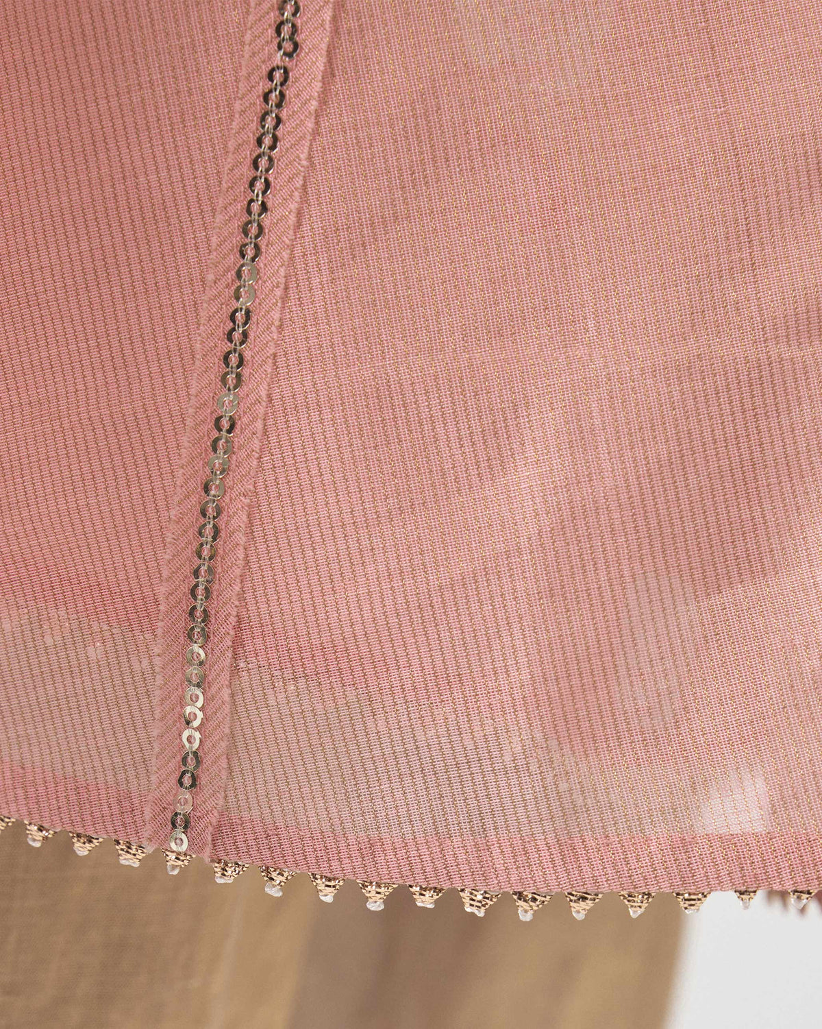 Close-up of sequin and beaded hem trim on a pink embroidered Sukhna kurta with slip.