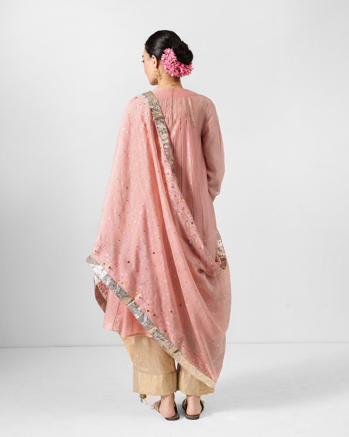 Back of a dust pink embroidered Lila dupatta with a metallic border draped on a person.