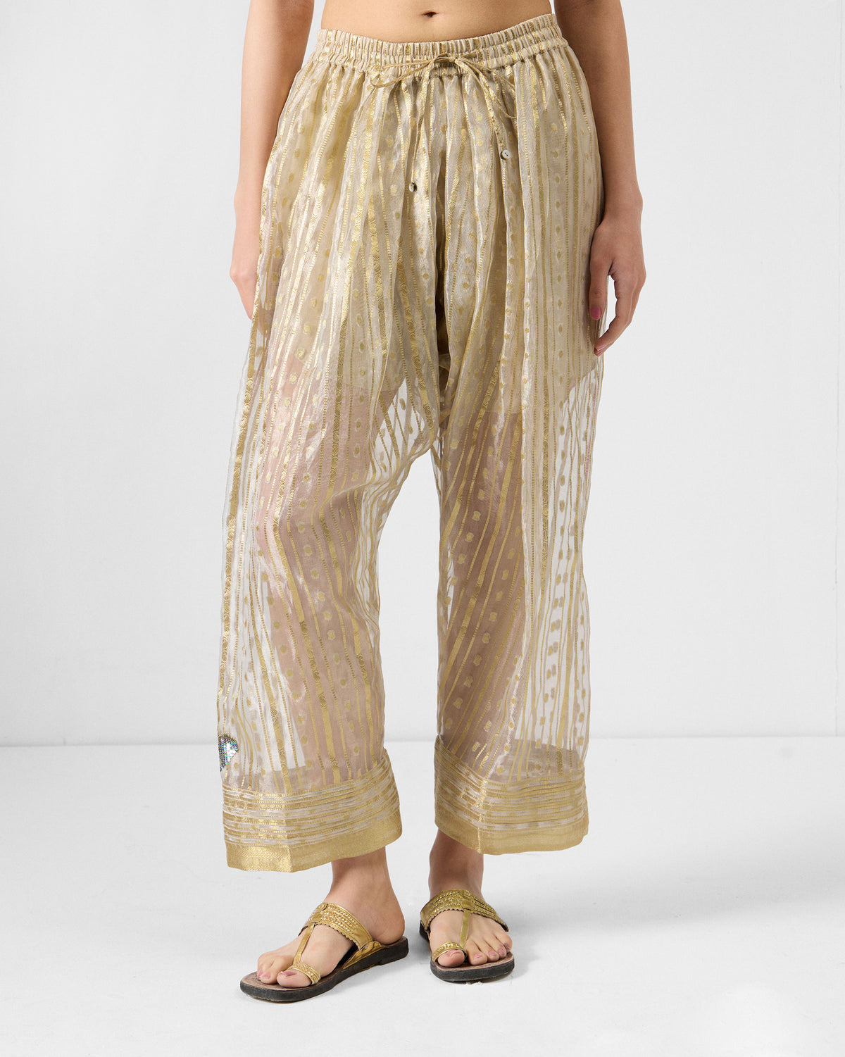 Person wearing a Ghoom Salwar in a sheer metallic stripe with a drawstring waist.