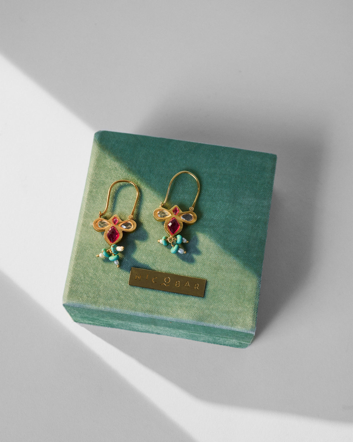 Gold doli earrings on a moss-green Nicobar velvet box.