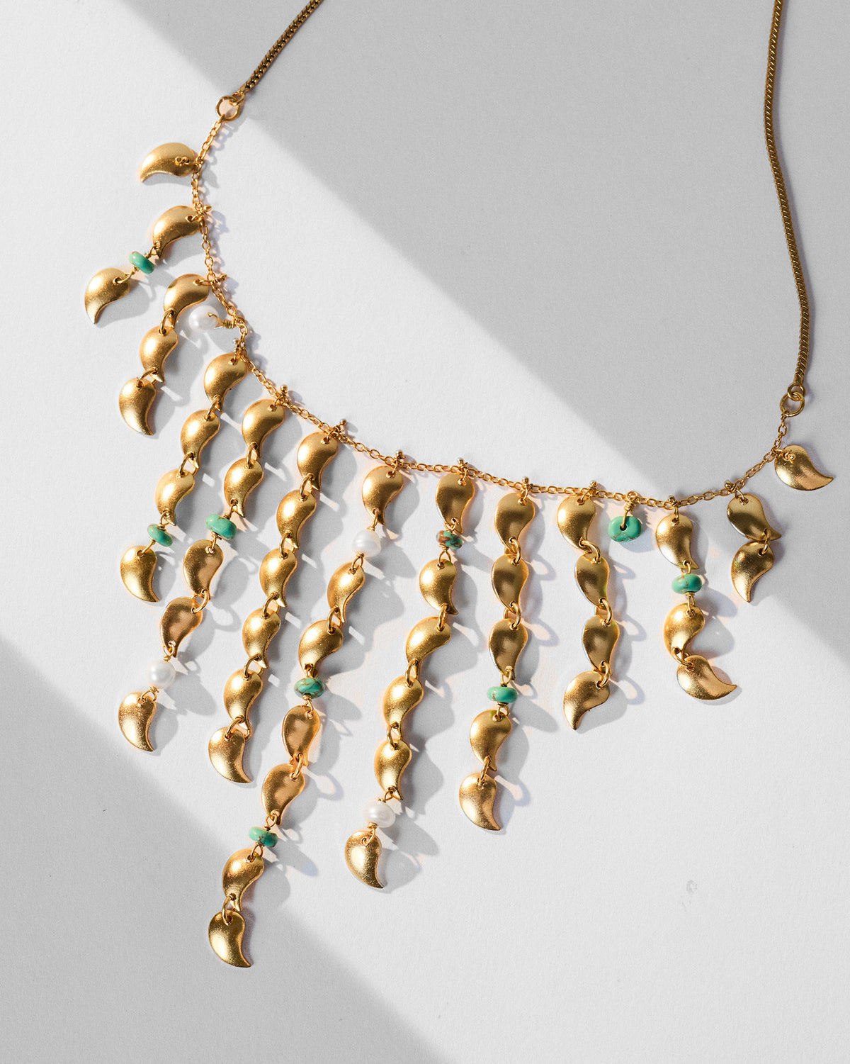 Gold Kairi fringe necklace showing mango charms with turquoise and pearl beads.