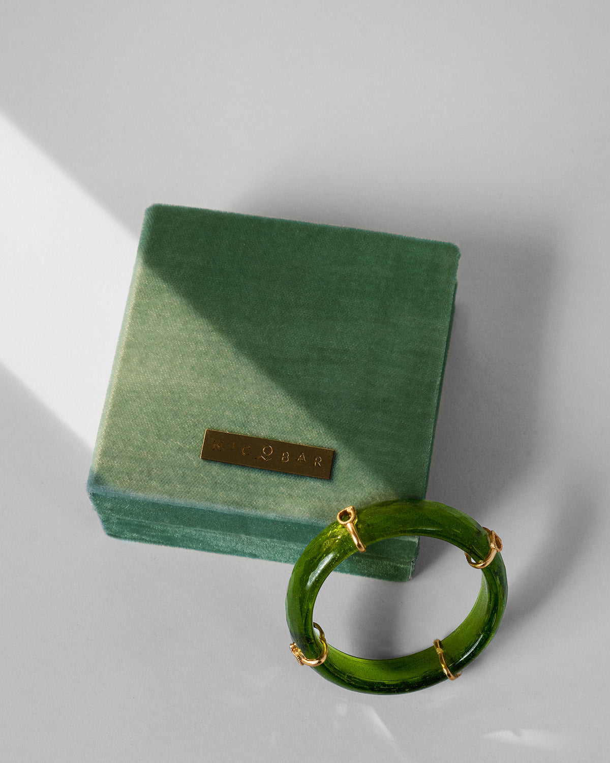 Green Ambi bangle with gold accents beside a green Nicobar gift box.