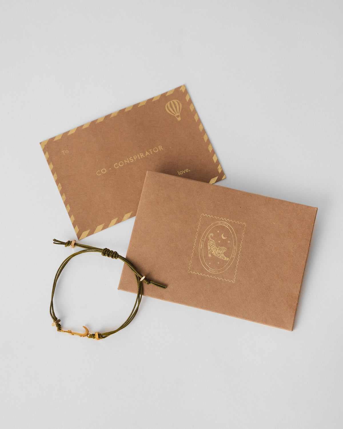 Green Croc Rakhi beside a kraft gift envelope and card.