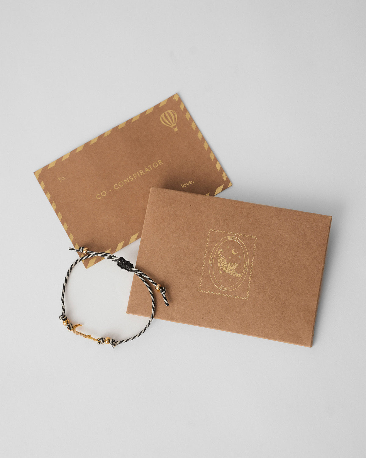 Croc Rakhi lying on a grey surface beside a kraft envelope.