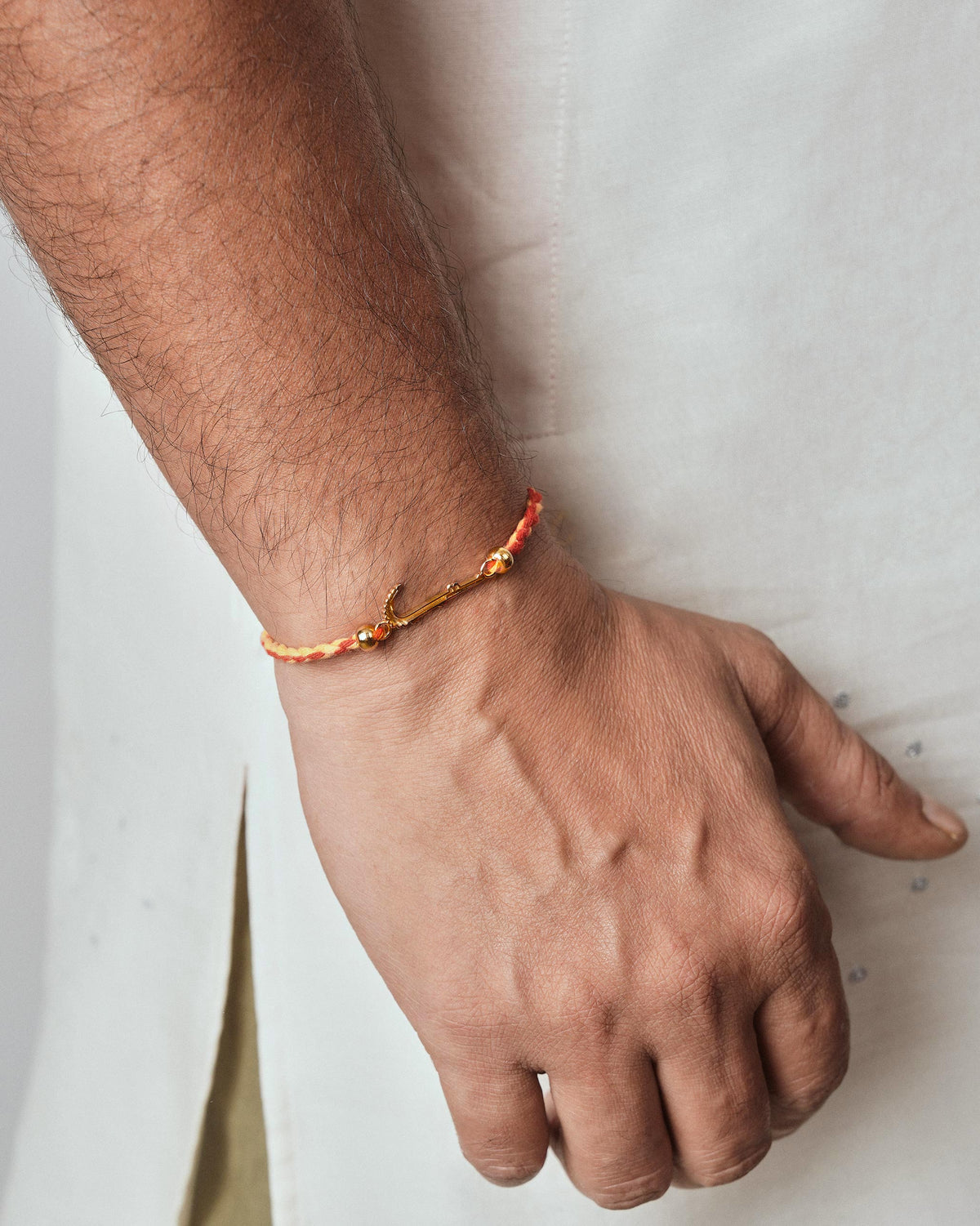 Person wearing a red Croc Rakhi with a gold charm.
