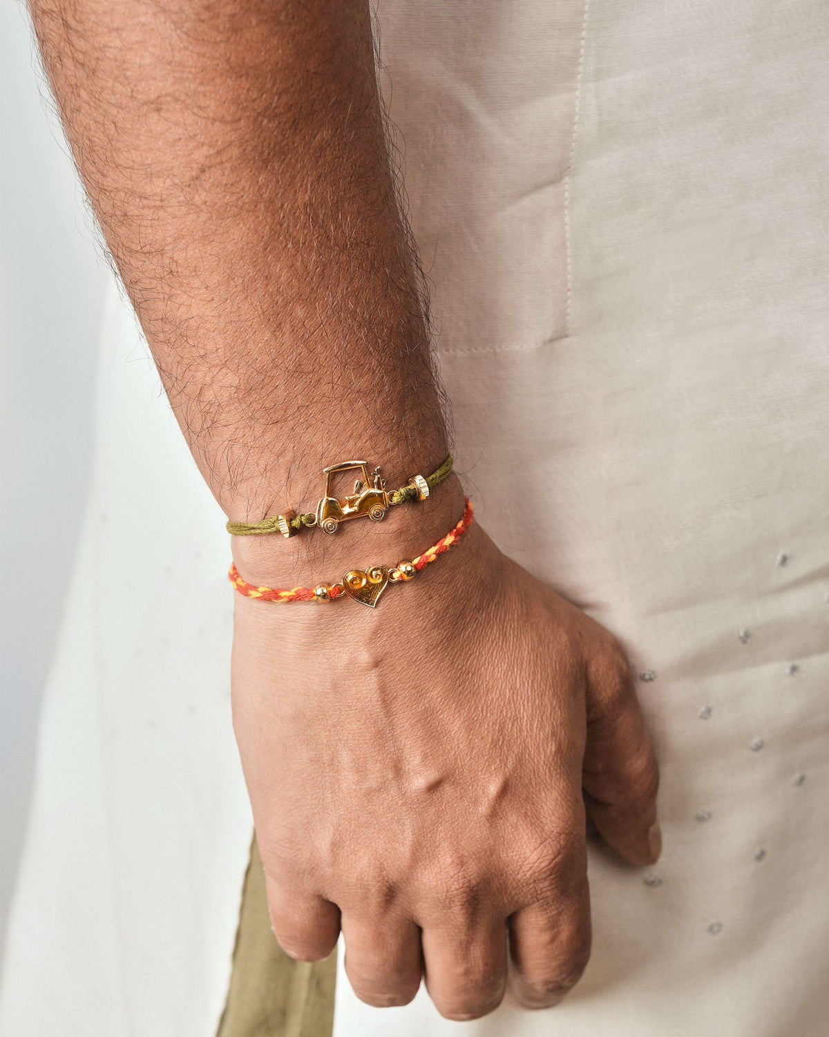Person wearing a Golf Cart Rakhi in olive green cord on the wrist.