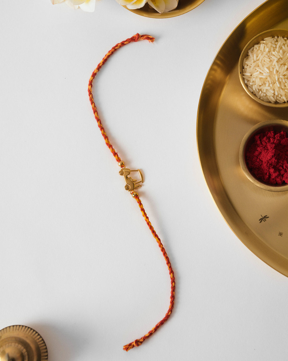 Golf Cart Rakhi in red and orange braid laid flat on a white surface.