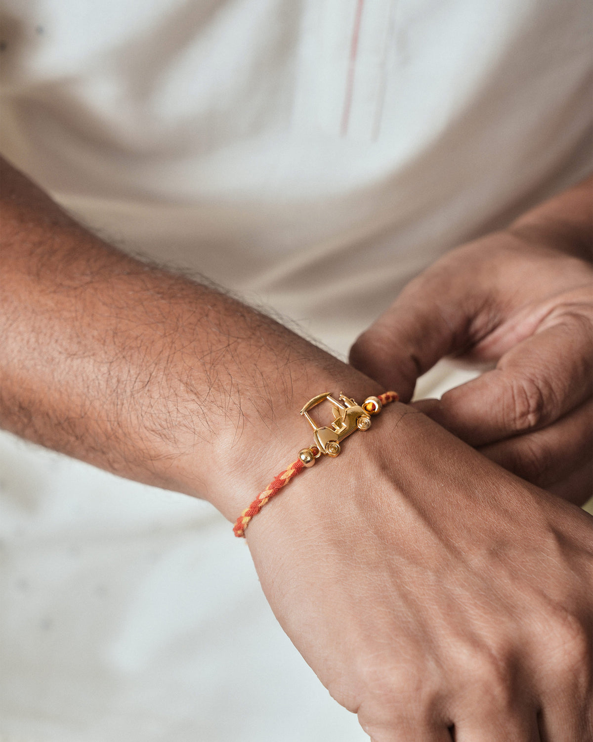 Person wearing a Golf Cart Rakhi in red and orange braid on the wrist.